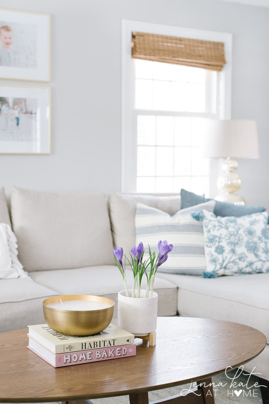 A close-up of the sofa, holding a trio of blue patterned throw pillows, with a lamp in the background 