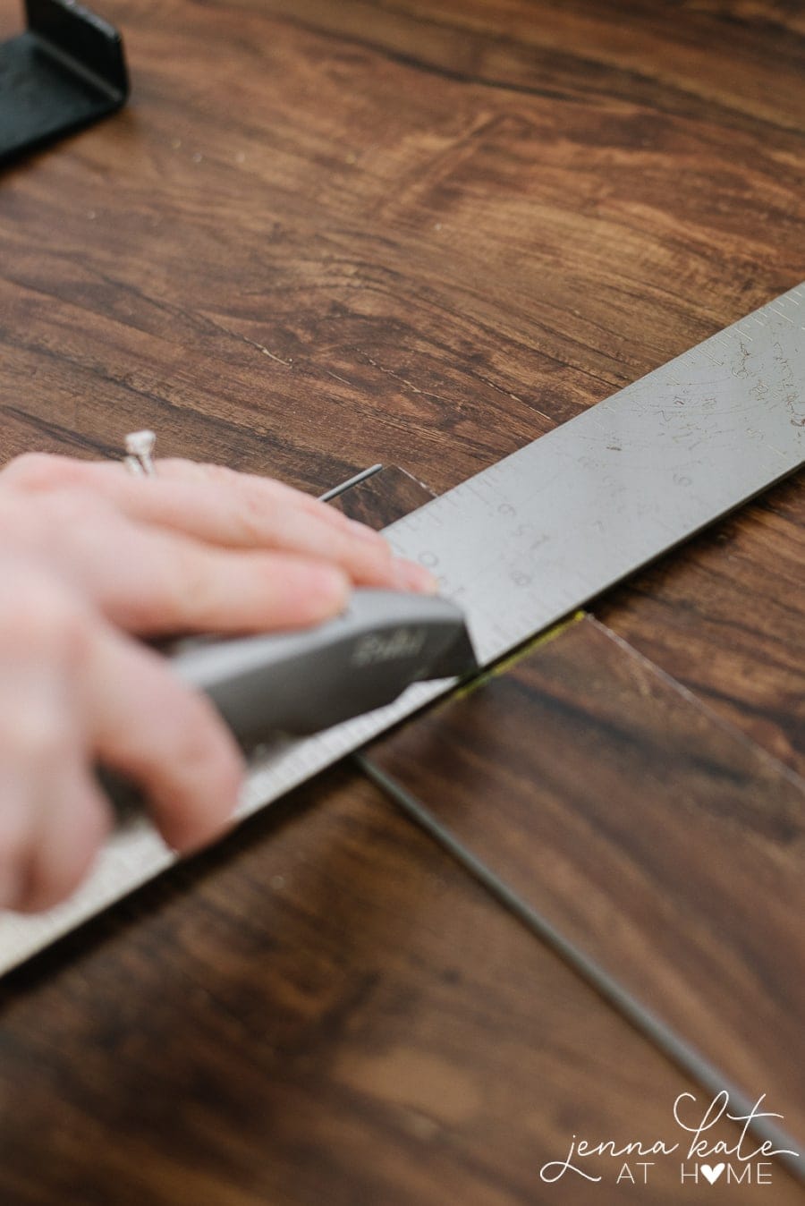 Using a box cutter to cut vinyl planks