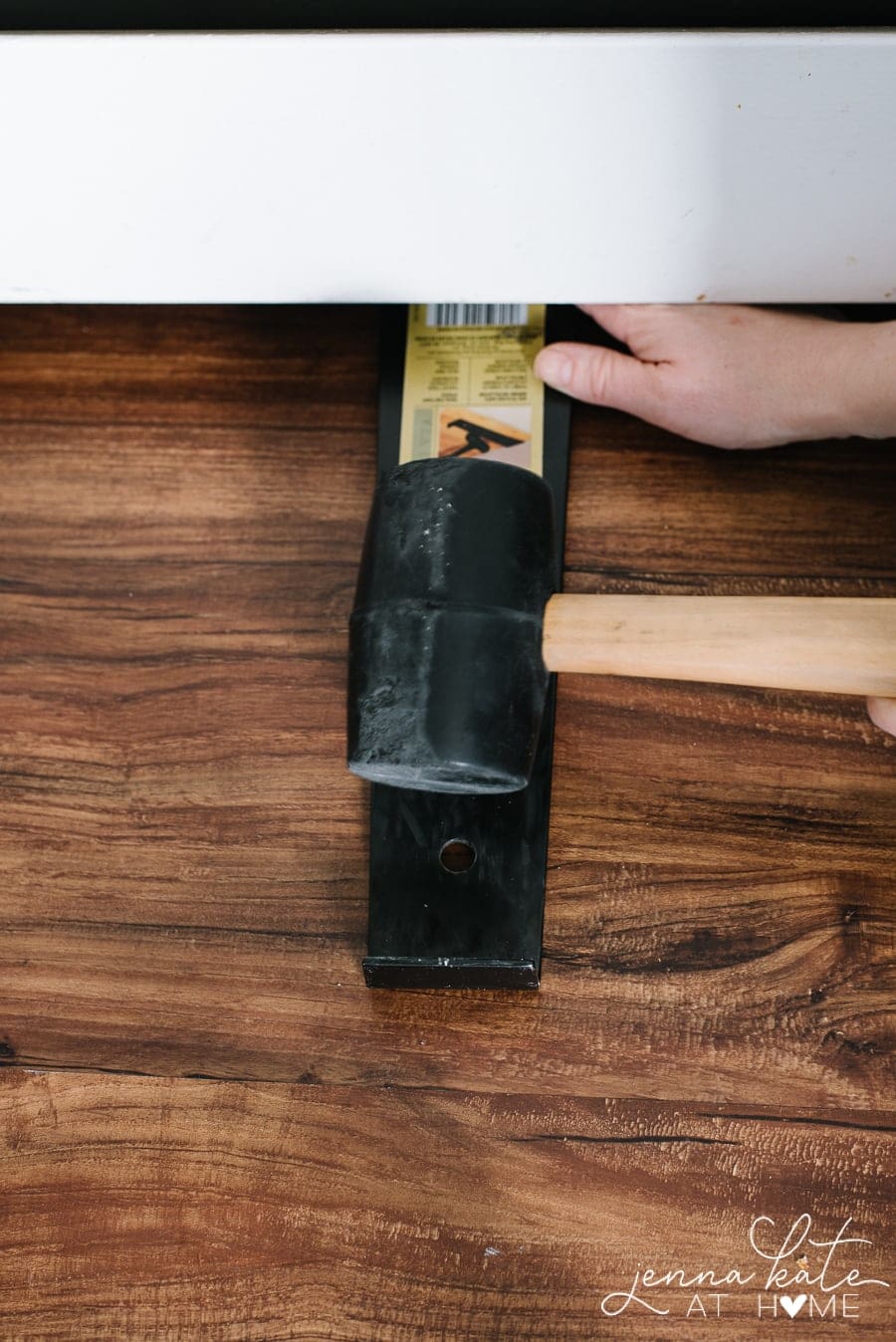 Using a rubber mallet to secure the vinyl plank floor