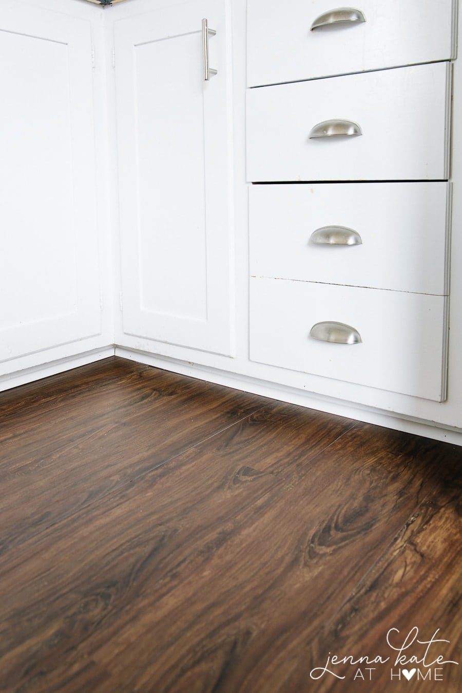 The edges of the luxury vinyl plank up against kitchen cabinets and secured with shoe molding