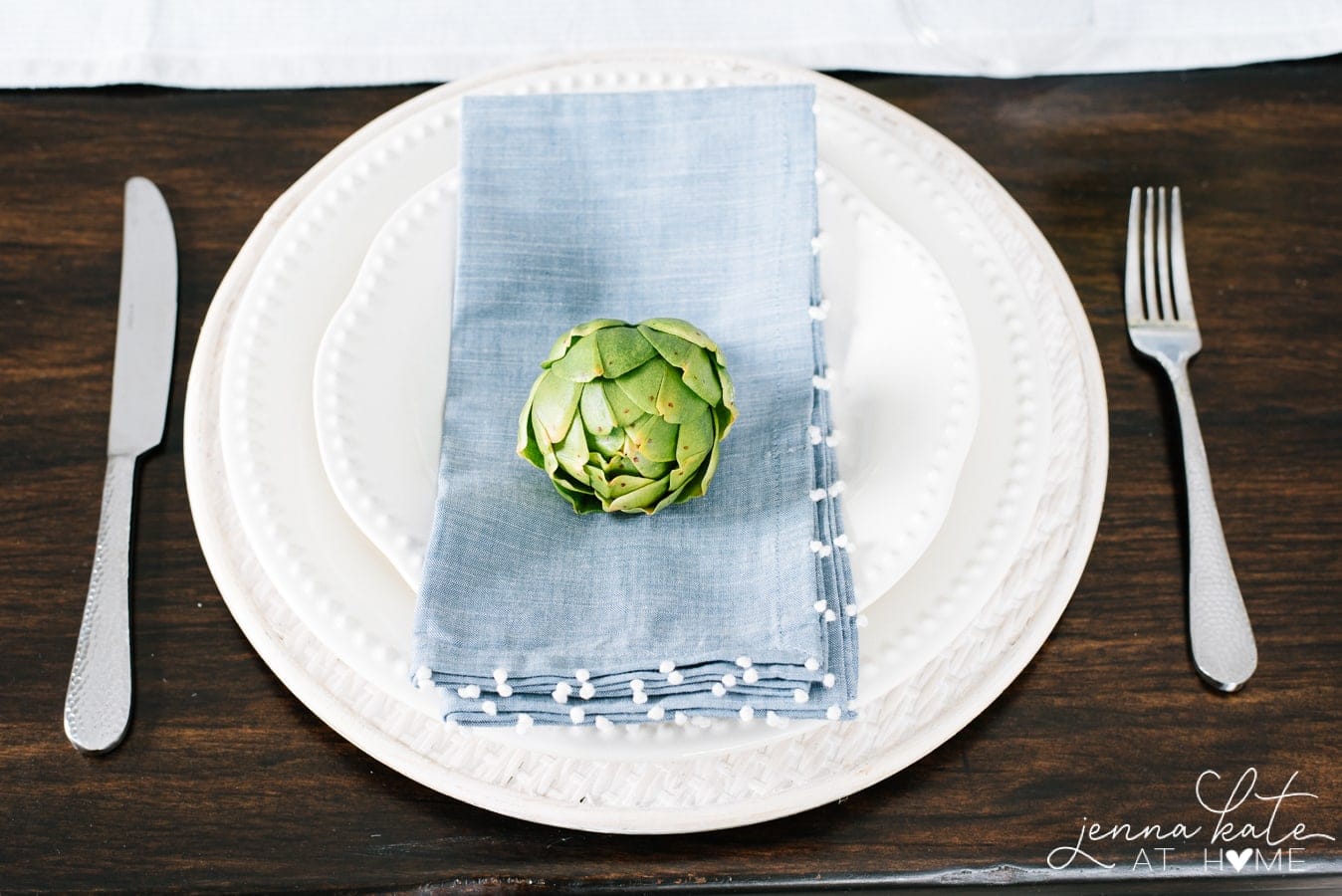 white dinnerware with blue napkin and faux artichoke