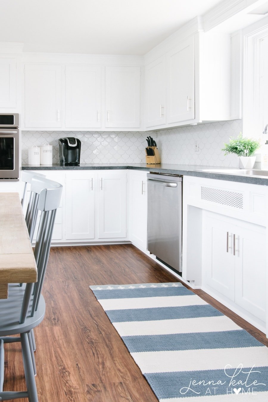 white kitchen with dark wood floors and a blue and white striped area rug