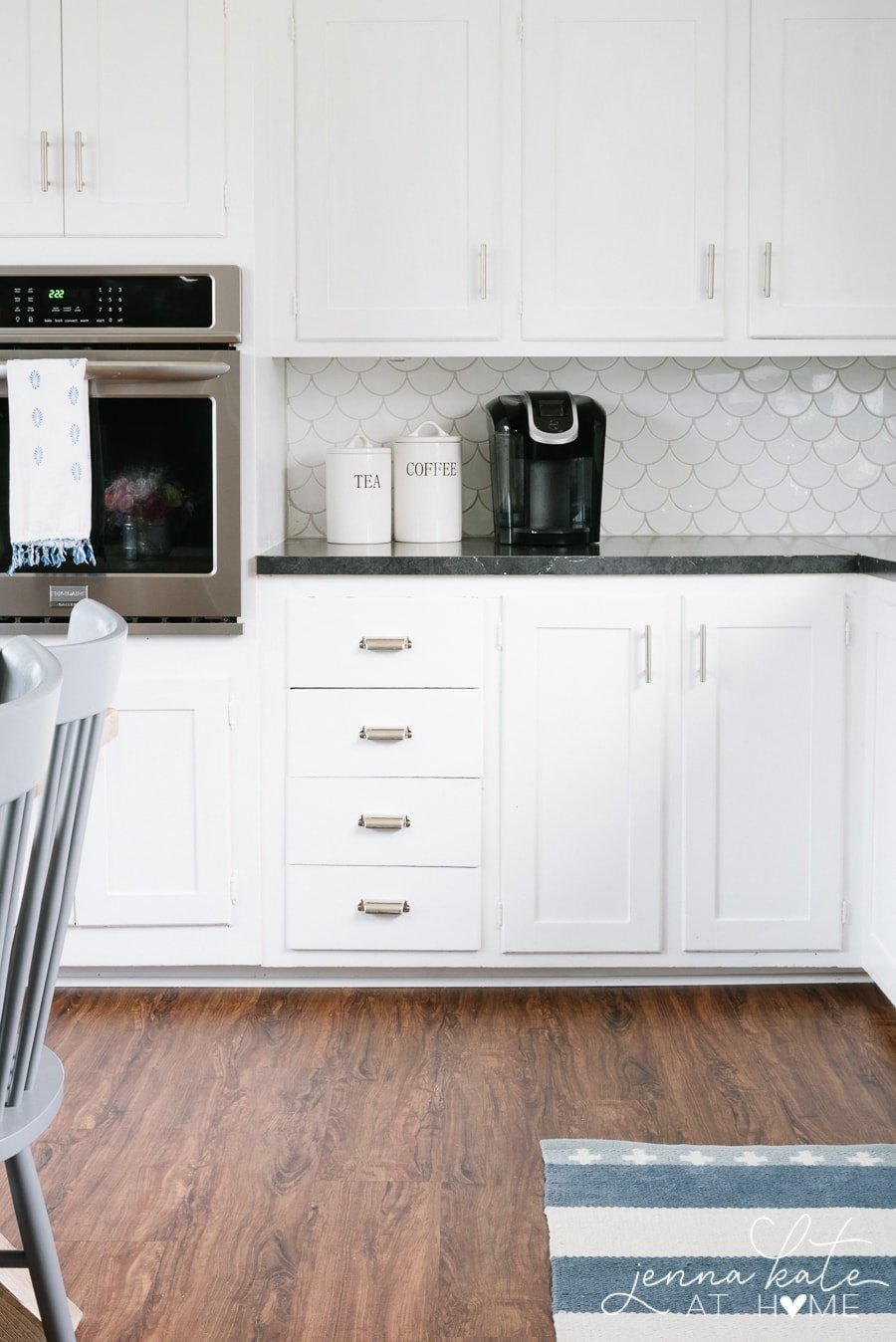 An stainless steel oven built into the white cabinetry, at counter height, 