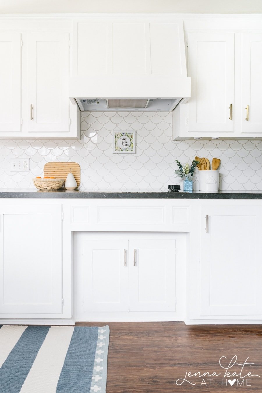 A stovetop with a large, white hood cover and white tile backsplash