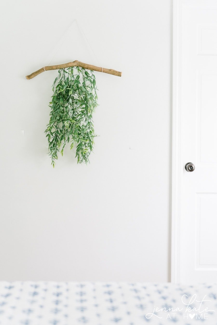 A loose arrangement of greenery hanging from a branch, hung on the wall