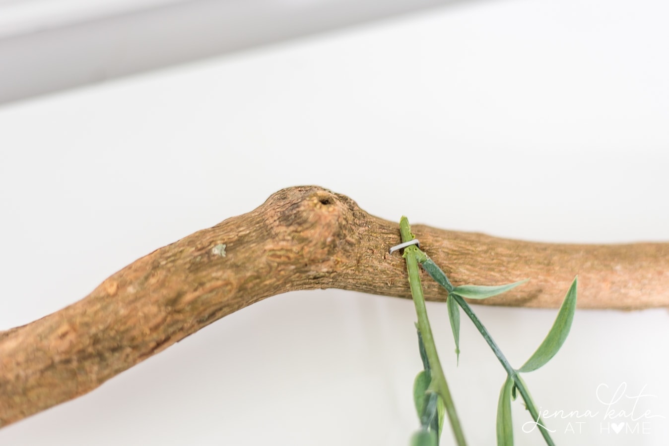 A close-up of the end of the clipped green garland seured to the branch with a heavy-duty staple
