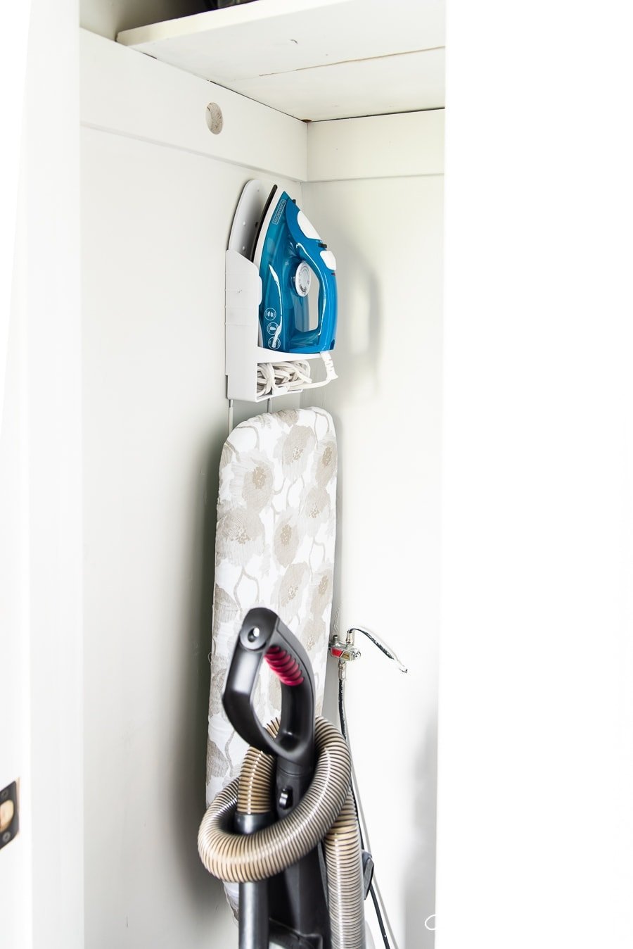 A close-up of wall-mounted holder for an iron and the ironing board