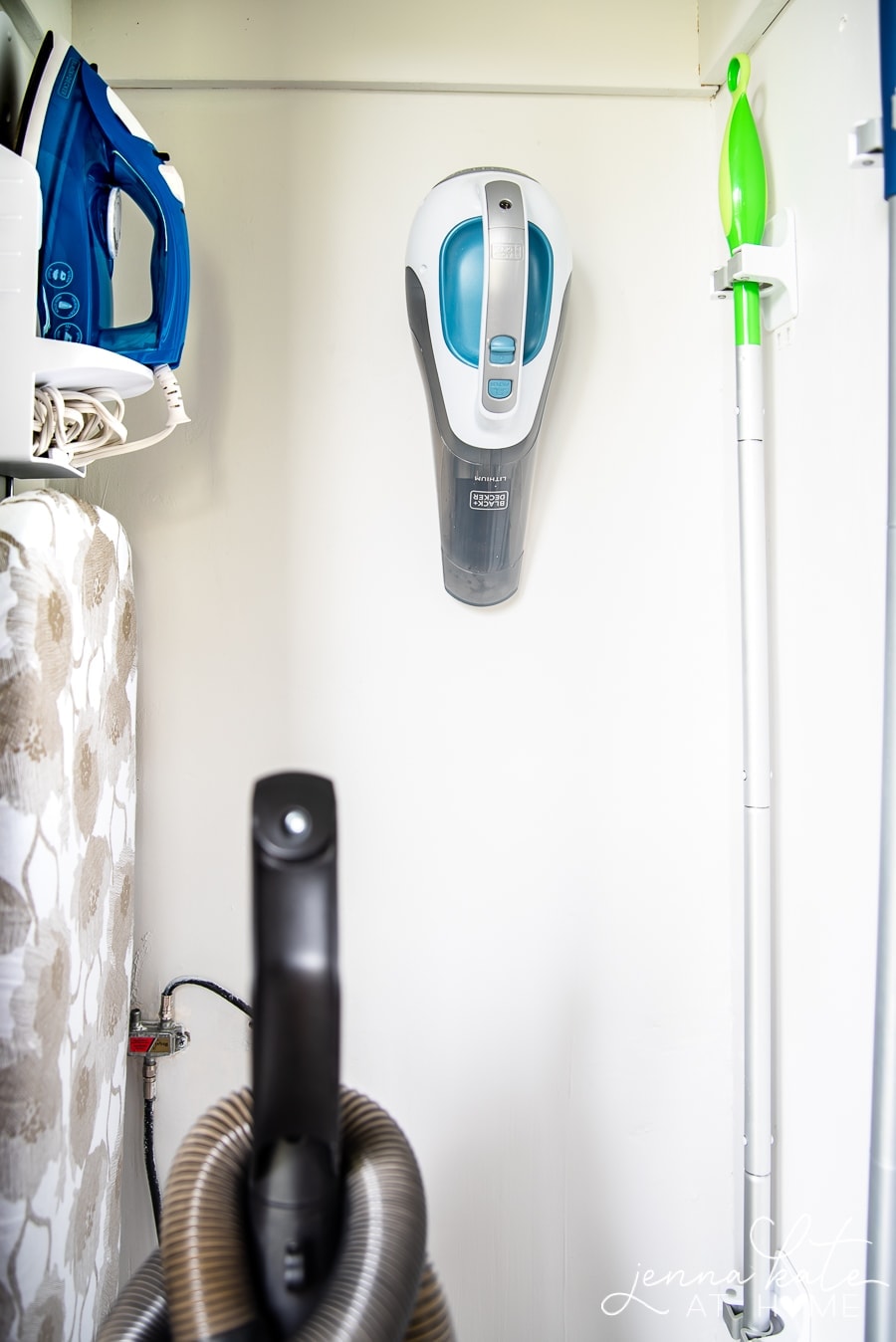 A close up a wall-mounted holder for iron and ironing board