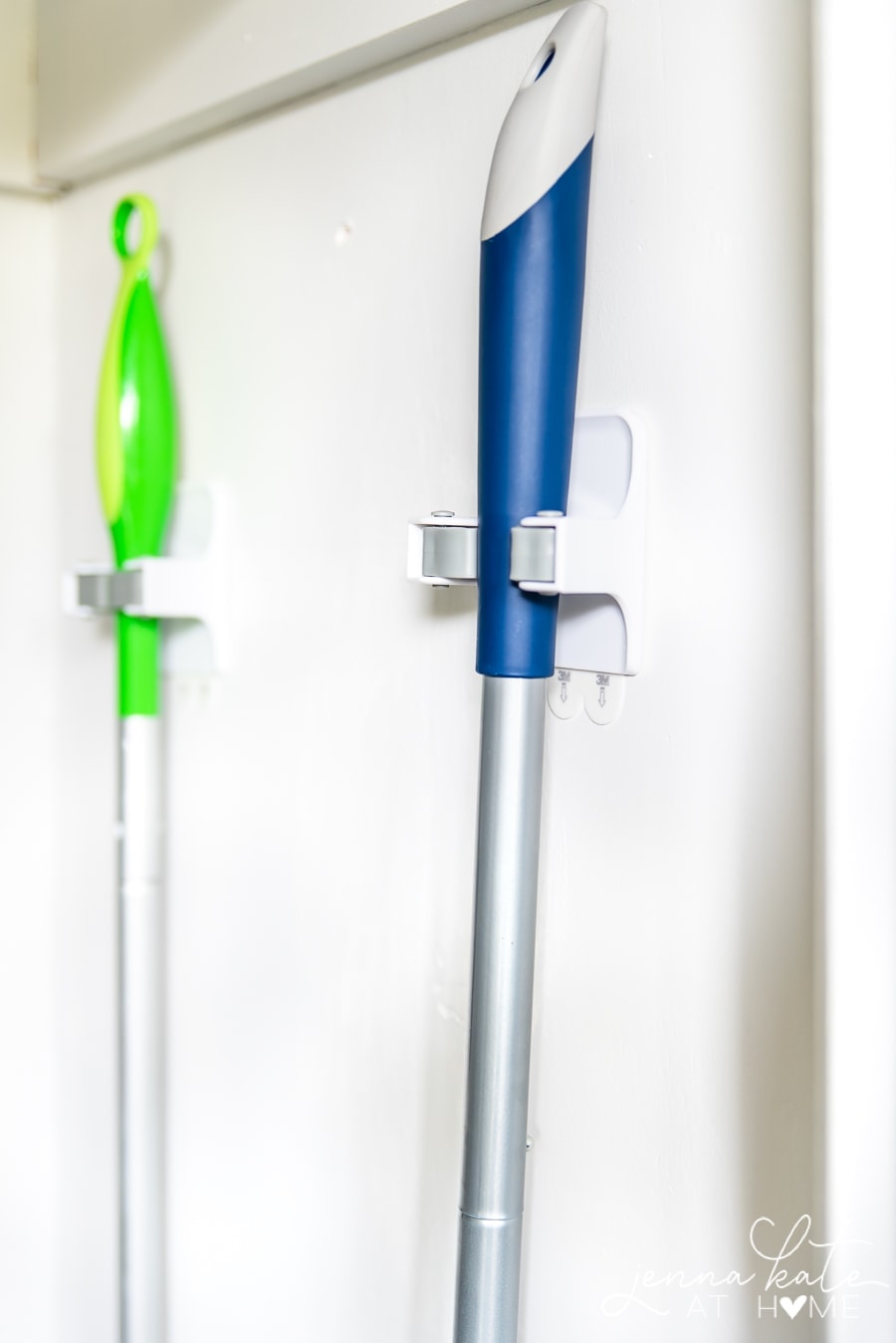 A close-up of wall-mounted clips that hold mop and broom handles in the closet