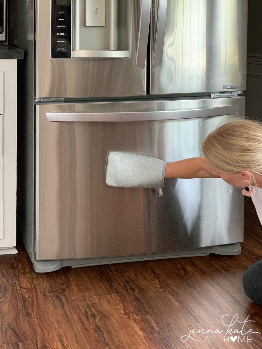 hand using cloth with olive oil to shine stainless steel refrigerator