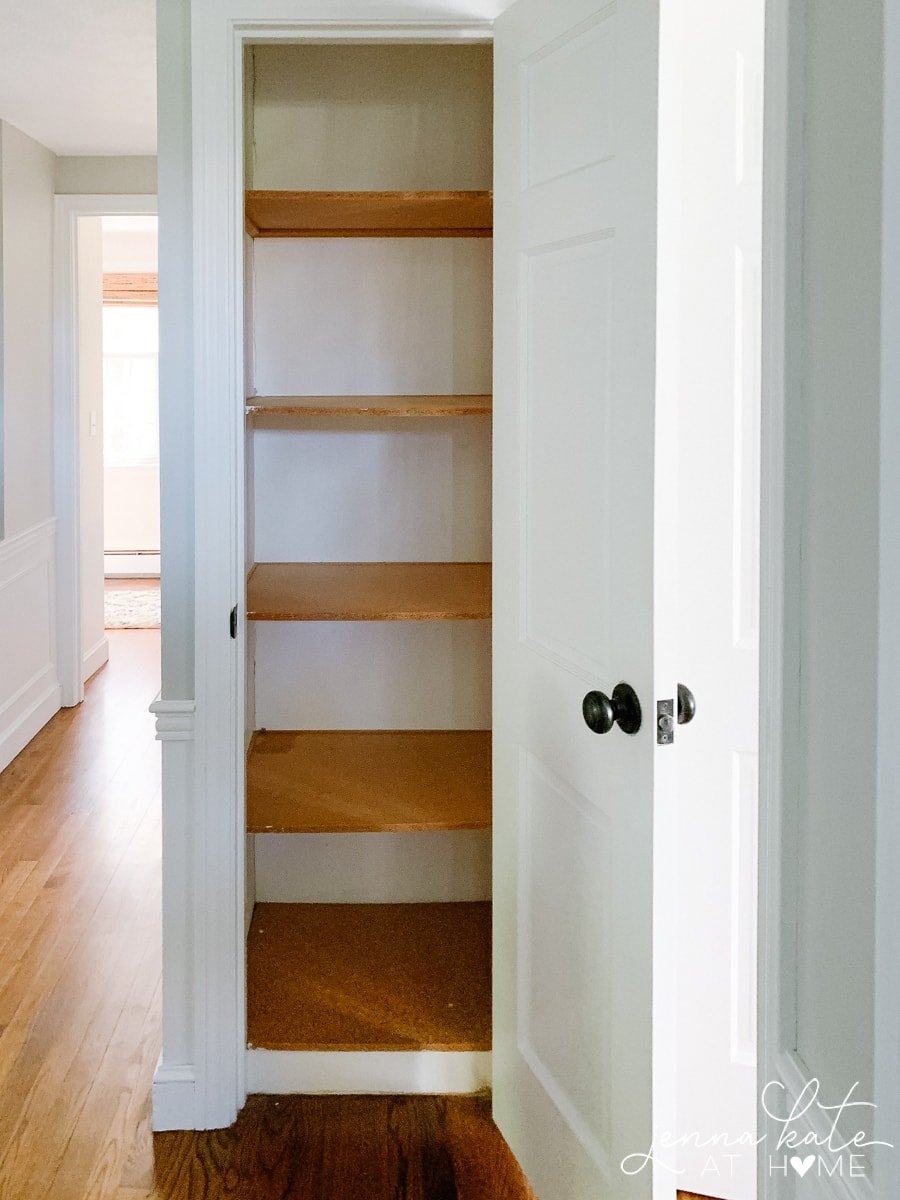 A narrow, empty closet containing 5 wooden shelves