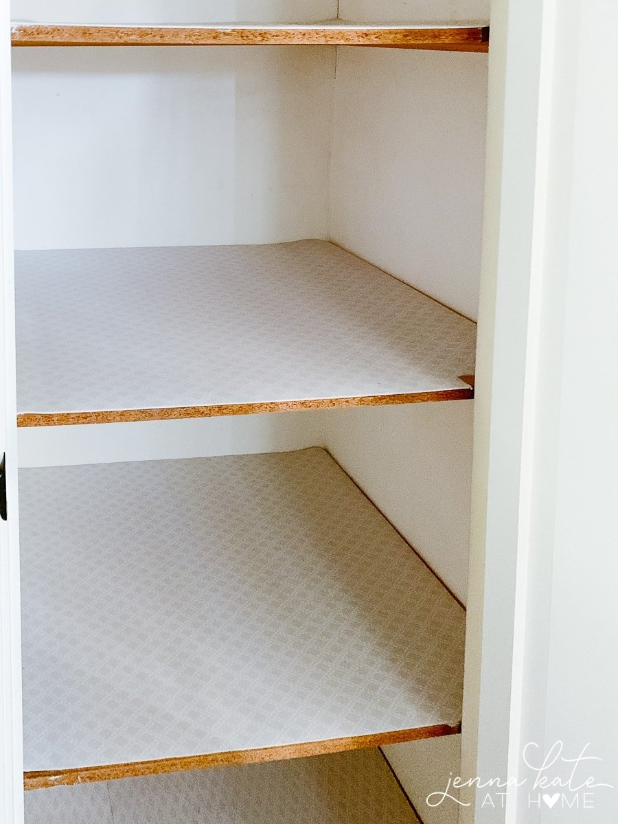 A close-up of two closet shelves lined with paper