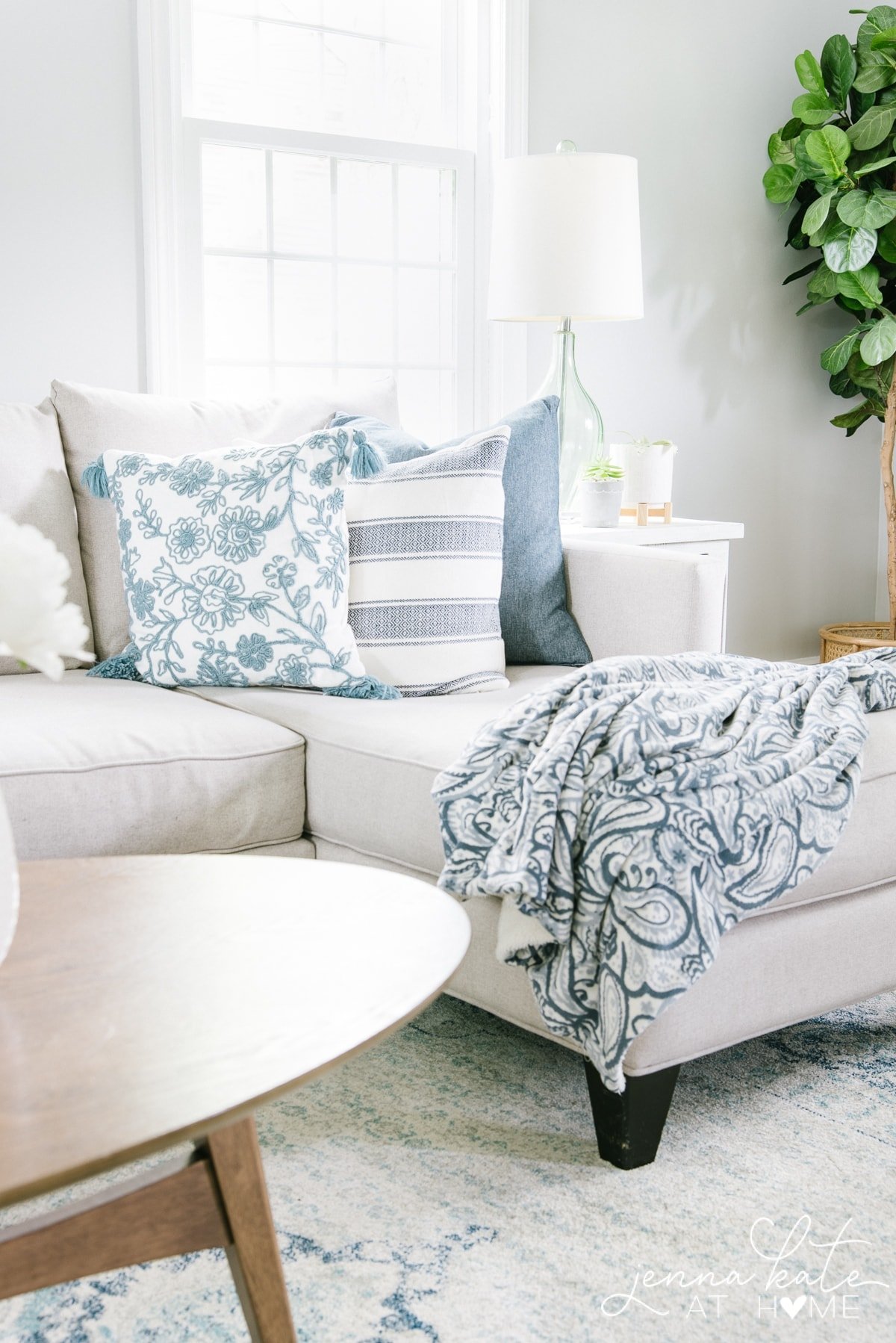 Decorating the living room couch with blue throw pillows and a matching blanket