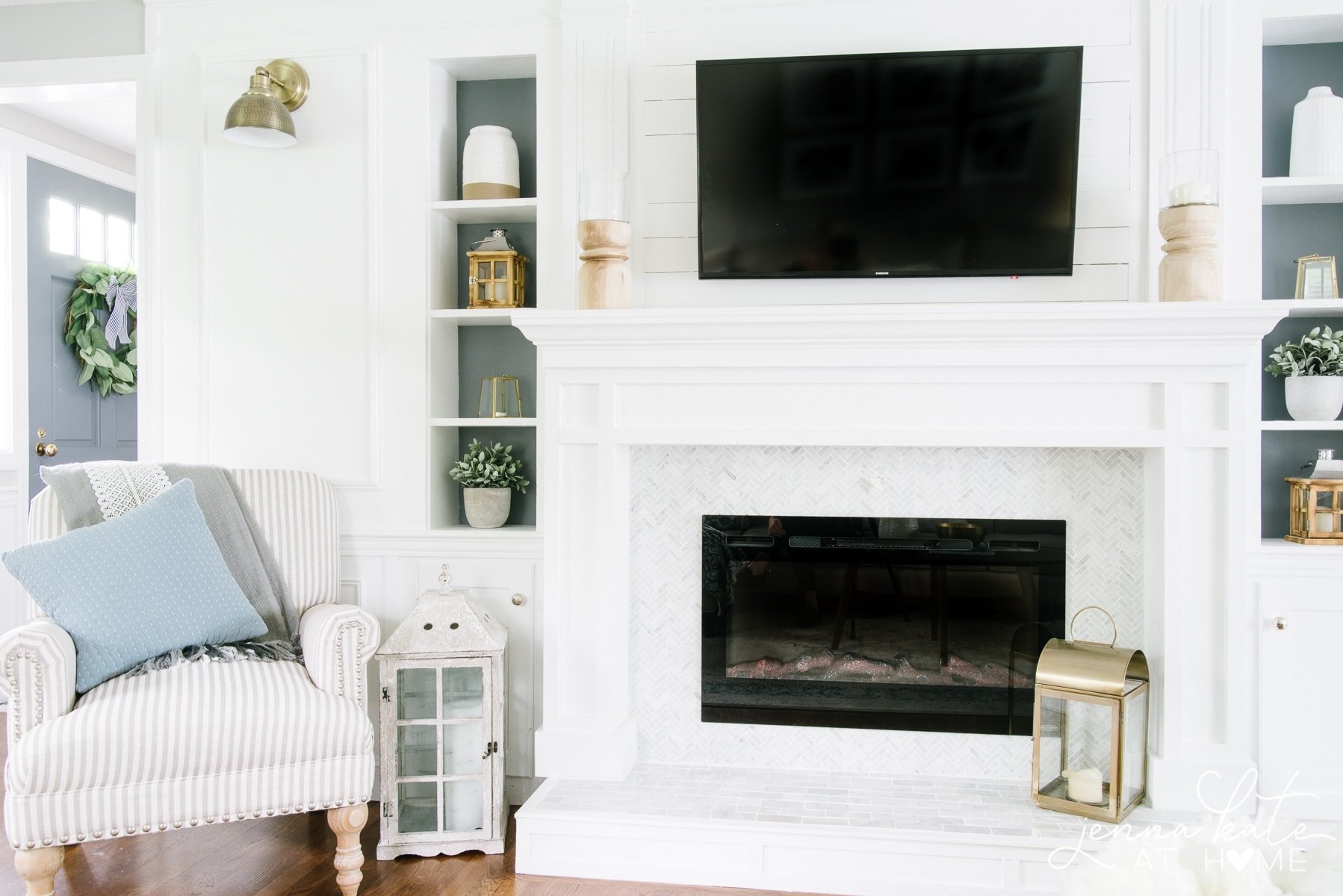 A white fireplace mantel with a mounted flat-screen TV and built-in shelves on the side