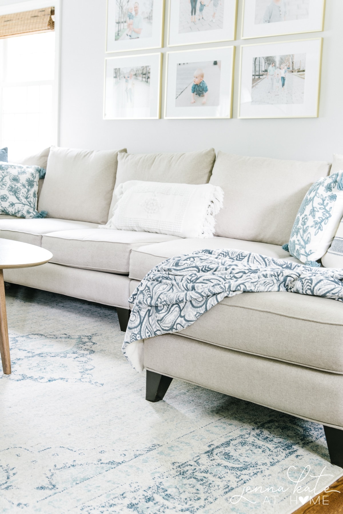 A white sofa with floral pillows and blue-patterned throw