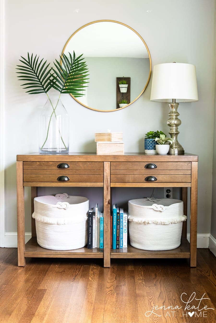 console table decorated for summer with palm fronds and white baskets underneath