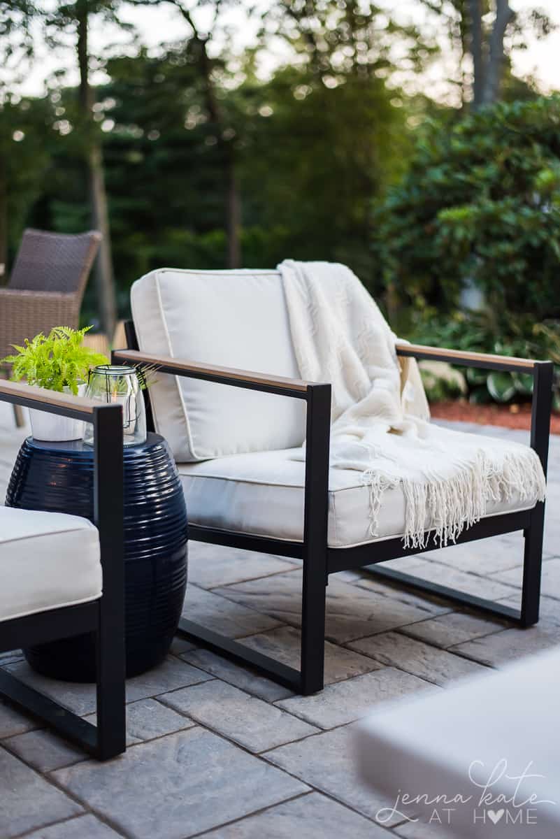 Stylish patio chairs with white curtains and a warm throw blanket