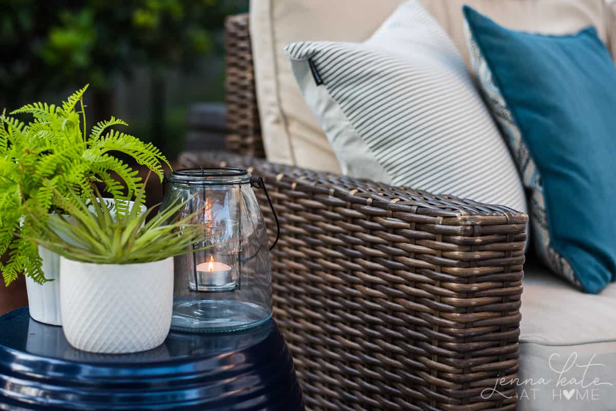 Our backyard patio has coastal decor like plants and blue and white throw pillows