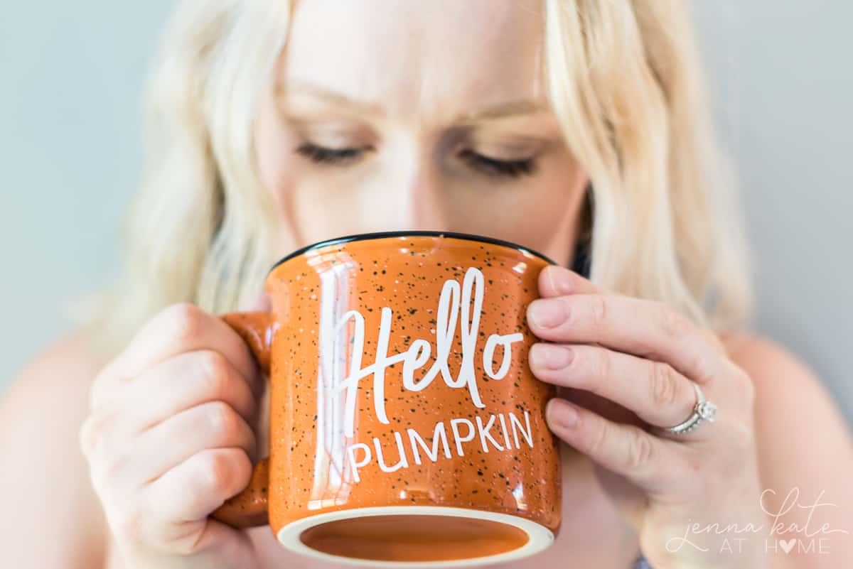 woman drinking from an orange campfire mug speckled with vinyl personalized writing