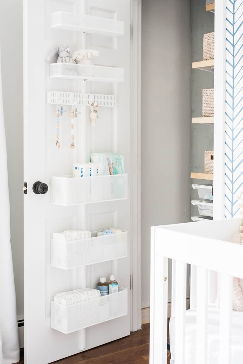 Shelves on back of a nursery closet door that store diapers and baby wipes