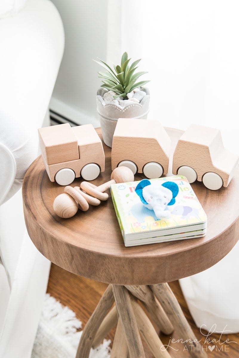 Side table with wooden train set, baby book and wooden rattle toy