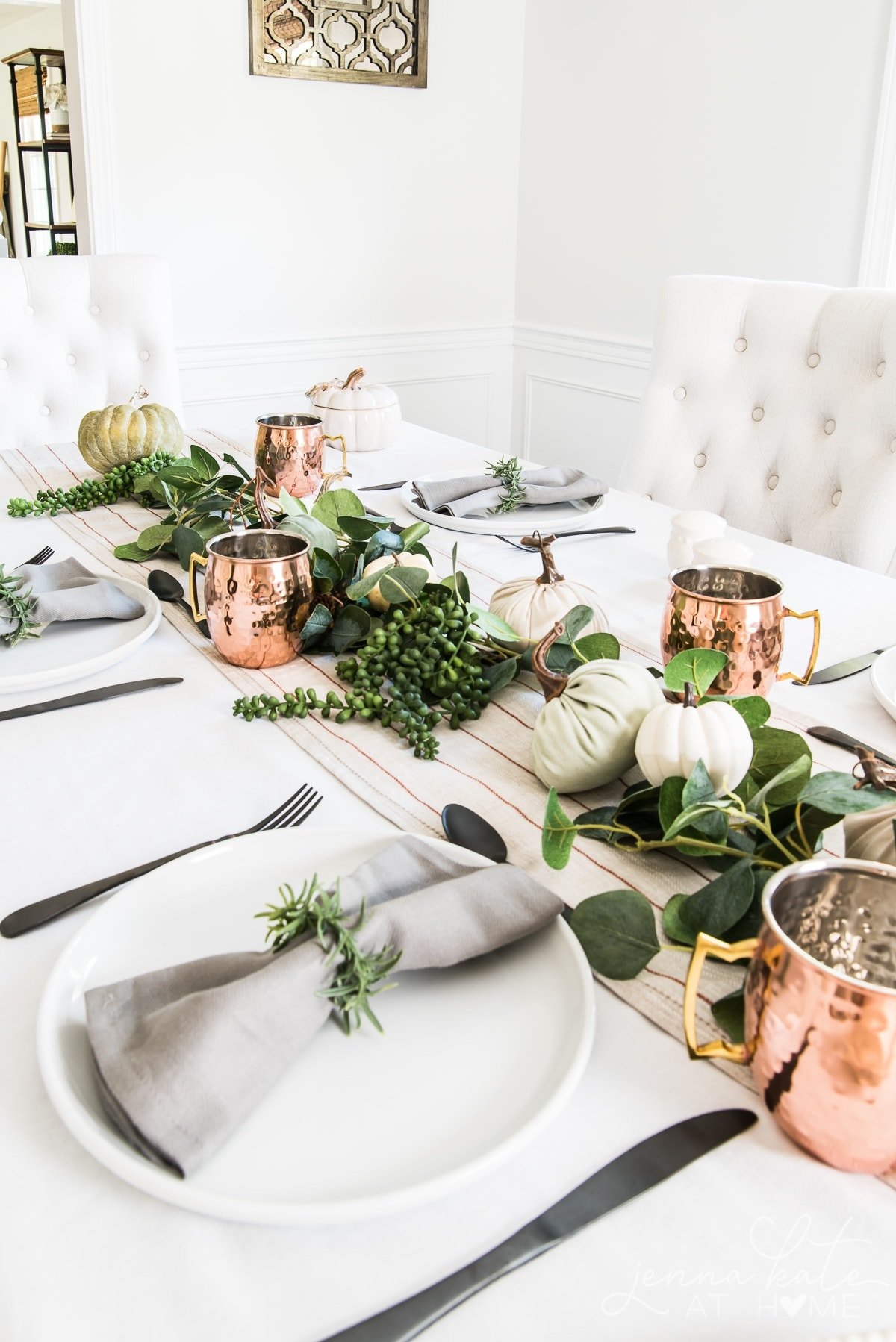 fall themed tablescape with pumpkins, copper mugs and greenery