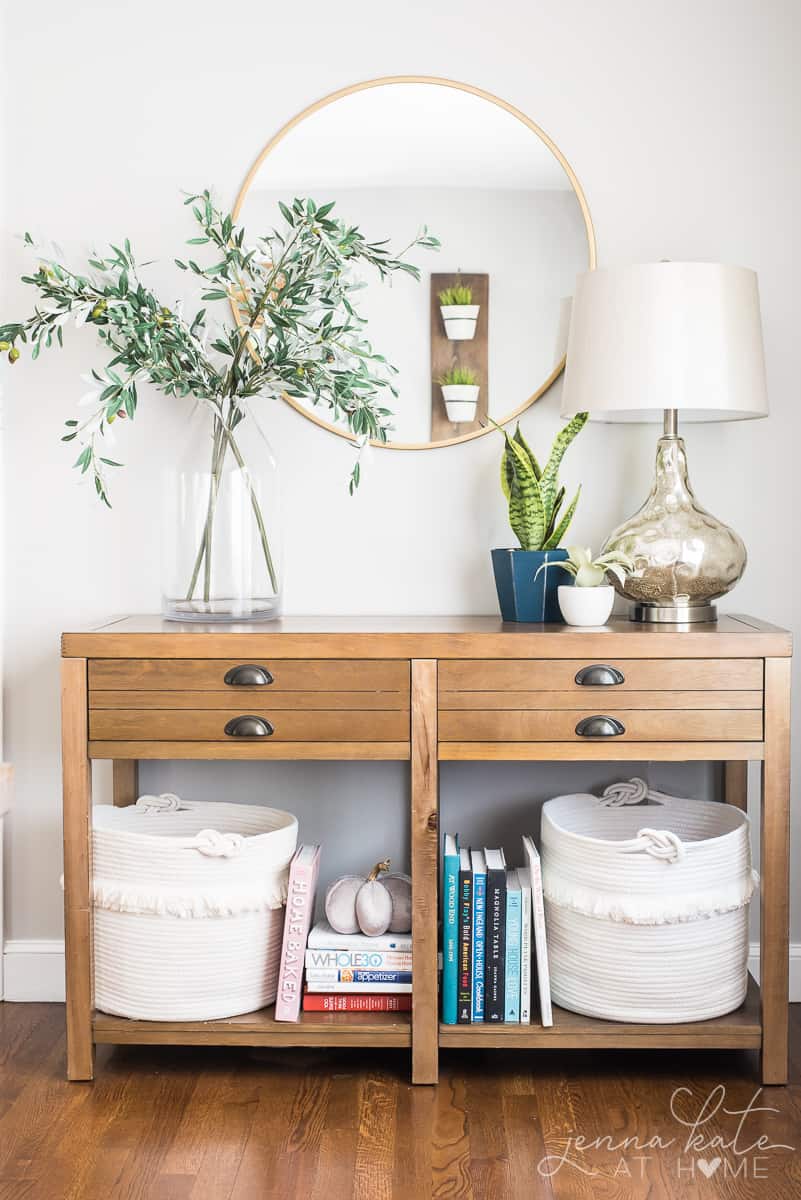 console table with fall foliage in a vase and a table lamp