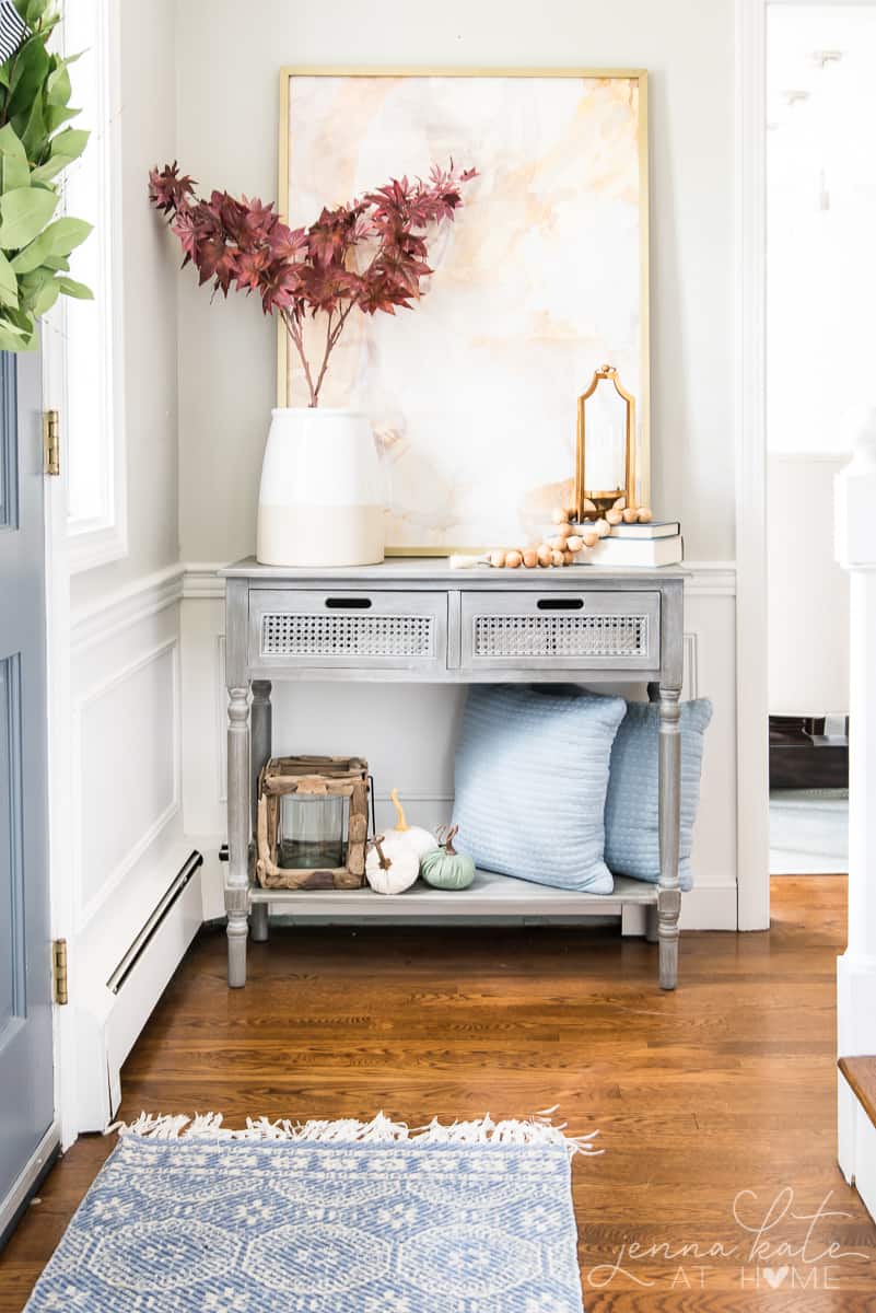 entryway console table with a large vase filled with red maple branches