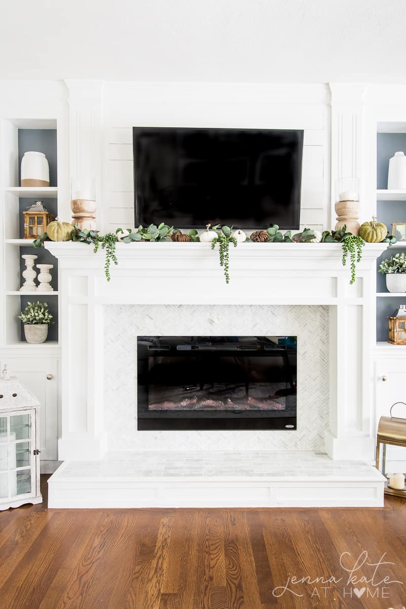 Fall mantel full of natural elements: pumpkins, greenery and wood tones