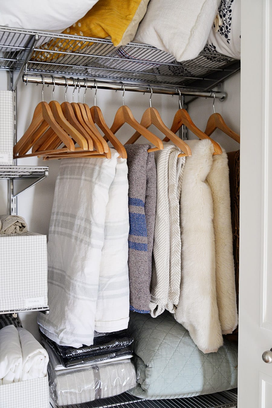 comforters and duvets hung on hangers inside a closet