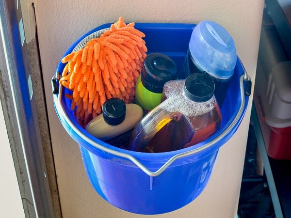 Car cleaning supplies in bucket hanging from garage wall