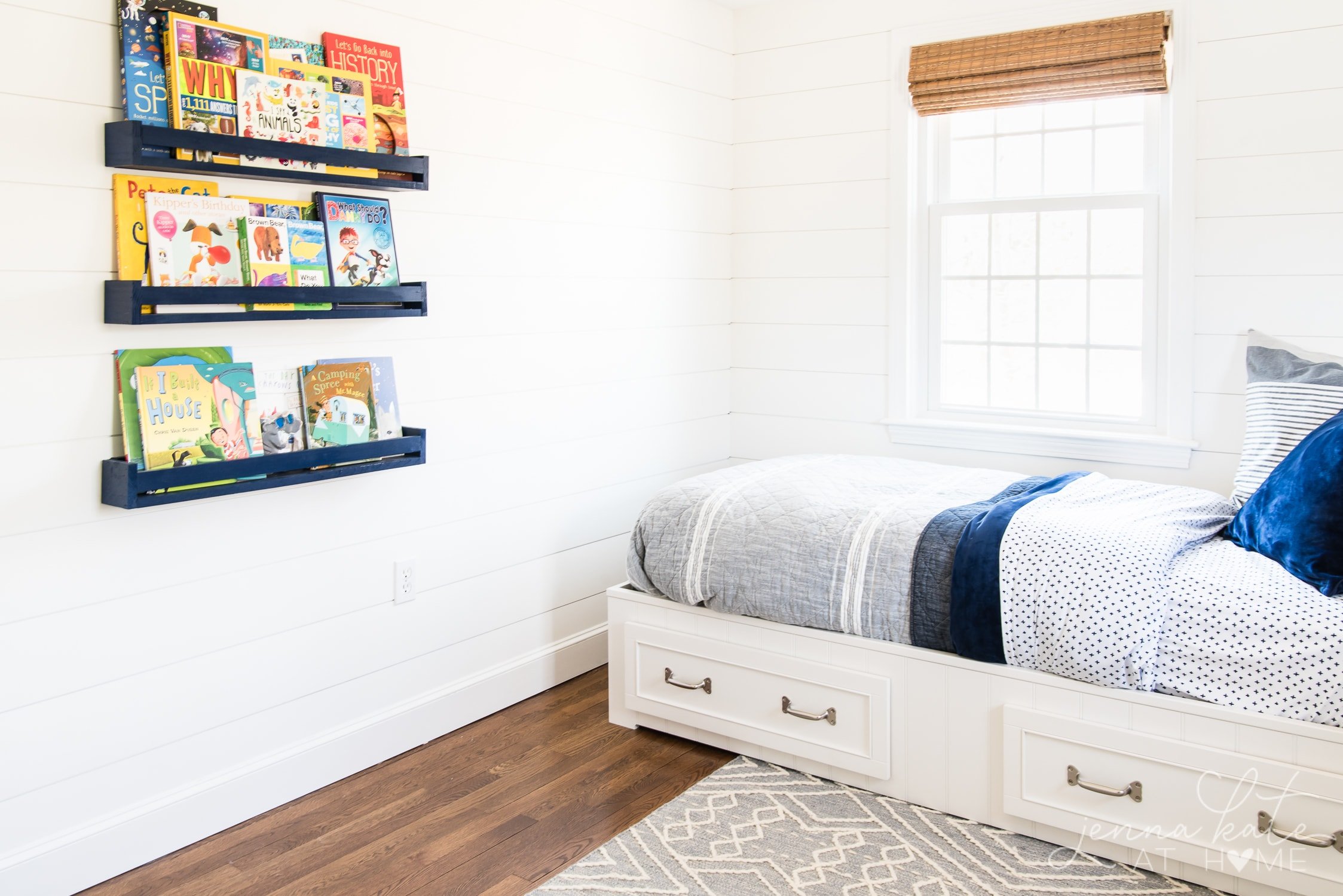 wall and trim in little boys bedroom painted BM Simply White with bed in the corner and book shelves on the other. 