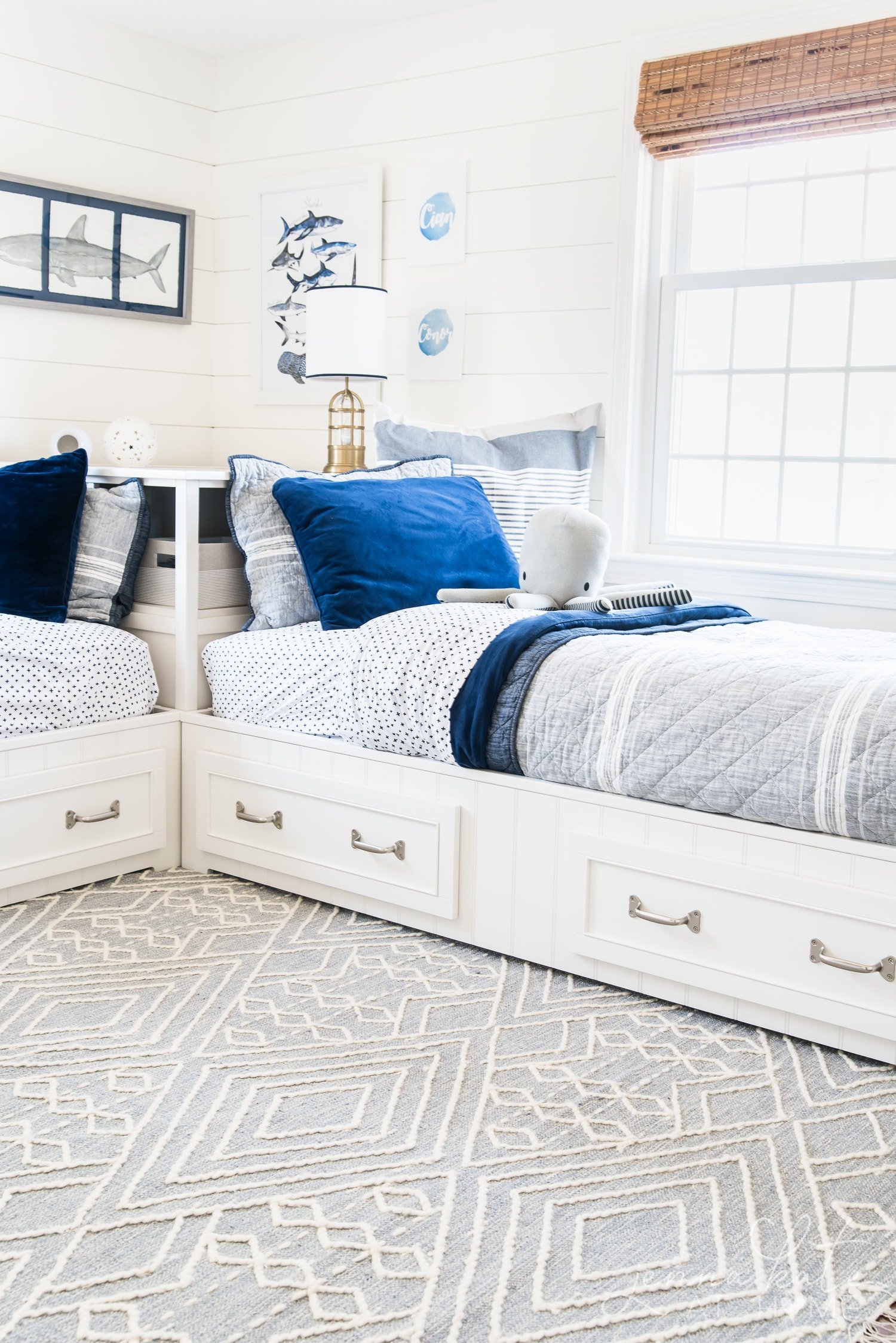 View of cozy beds in awesome kids room with a new patterned rug and toy octopus one of the beds