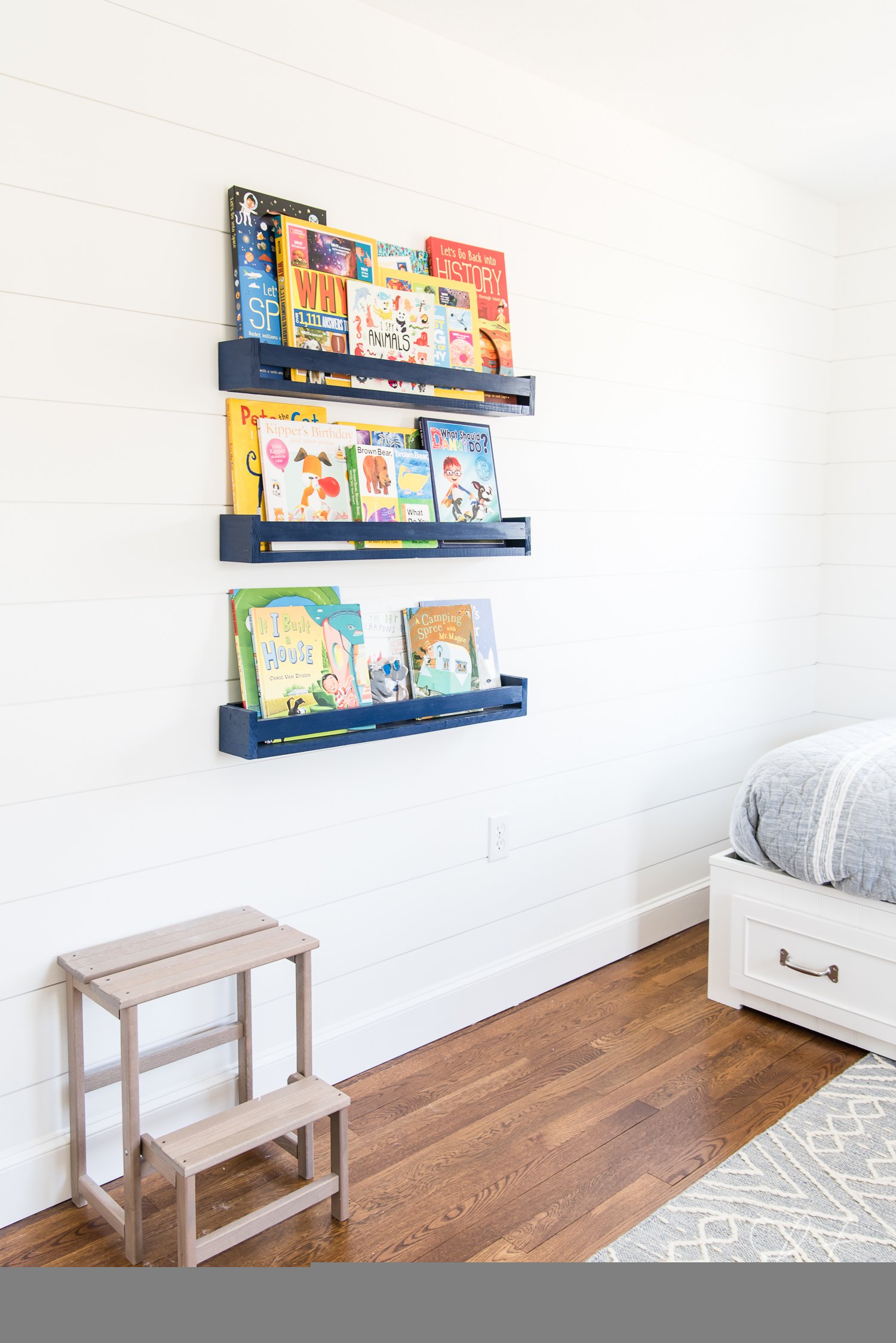 DIY book navy blue book ledges filled with kid's books form part of the decor