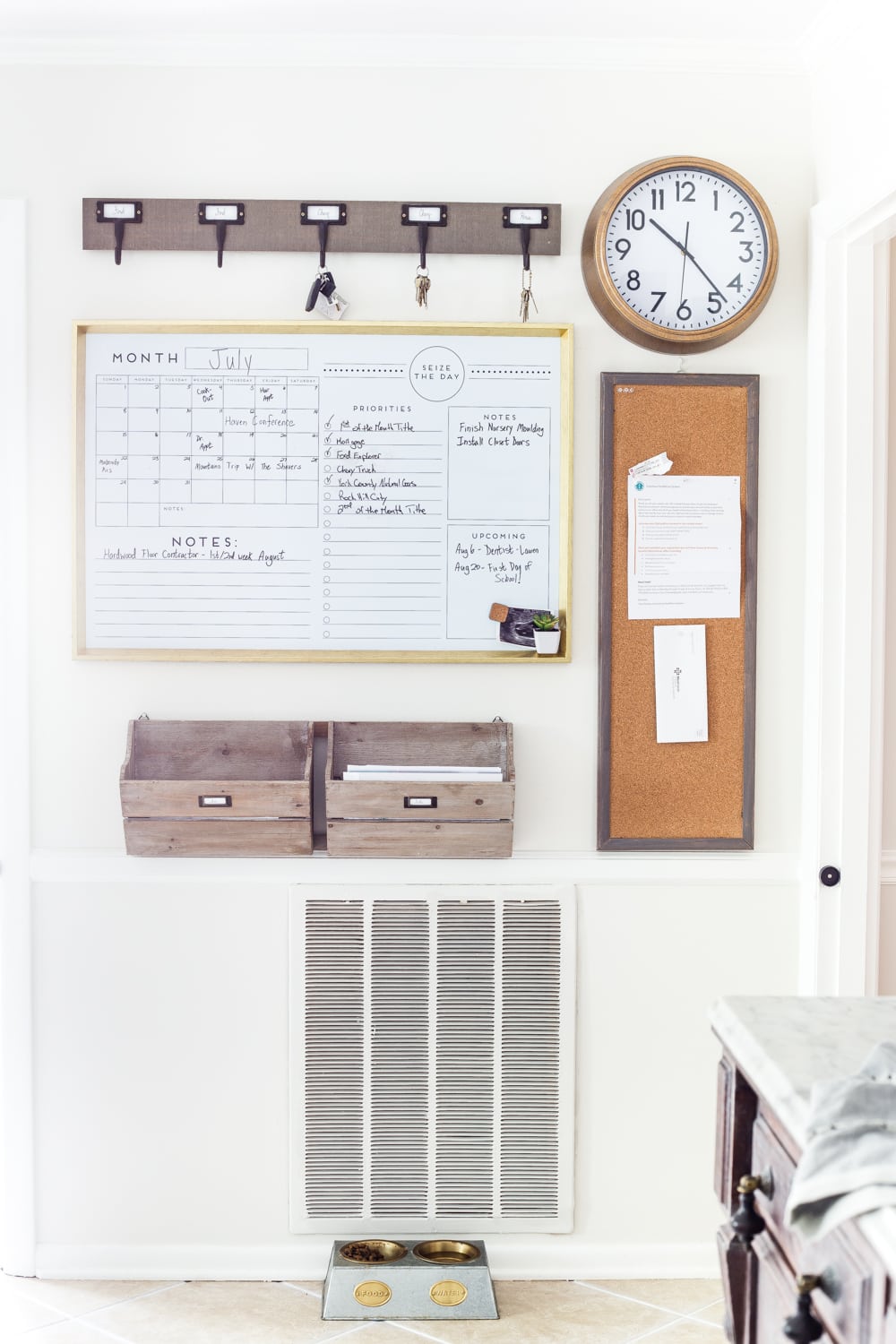Large whiteboard calender, key hooks, clock, bulletin board and wooden crates for filing papers