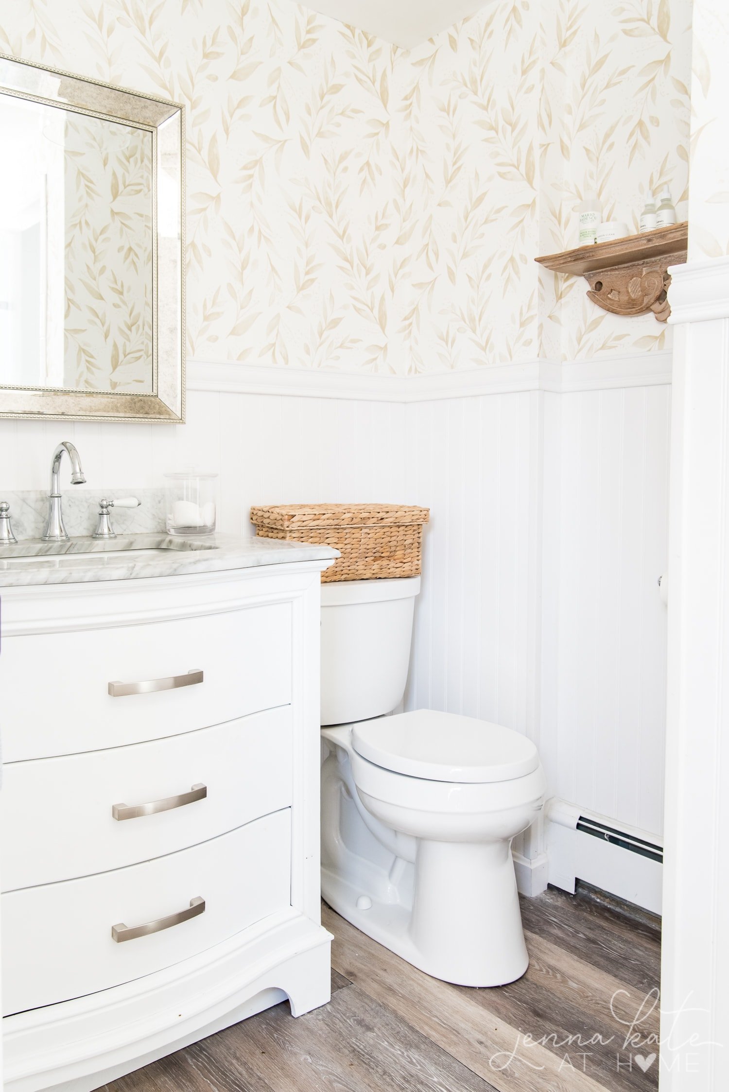 A close up of a sink and toilet with wallpaper on the bathroom walls