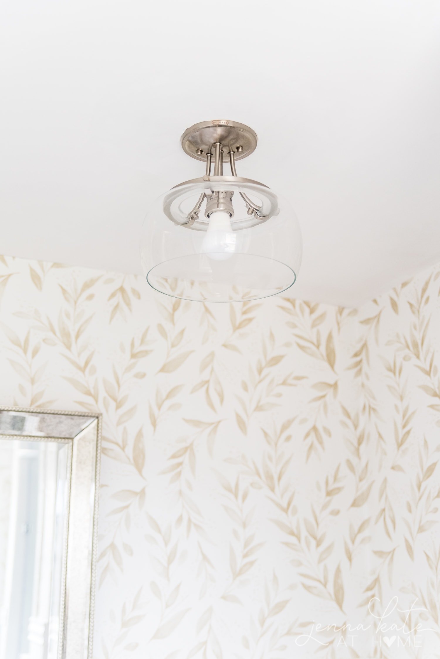 Clear glass light fixture against backdrop of new wallpaper