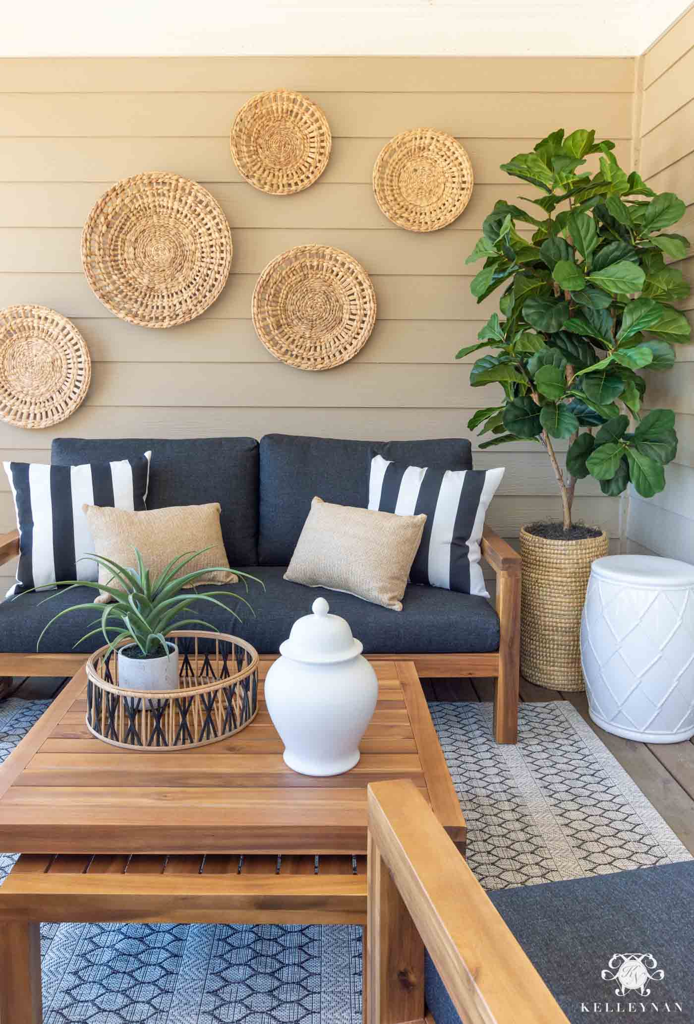 Simple porch decor with gray couch and baskets hanging on the house's siding