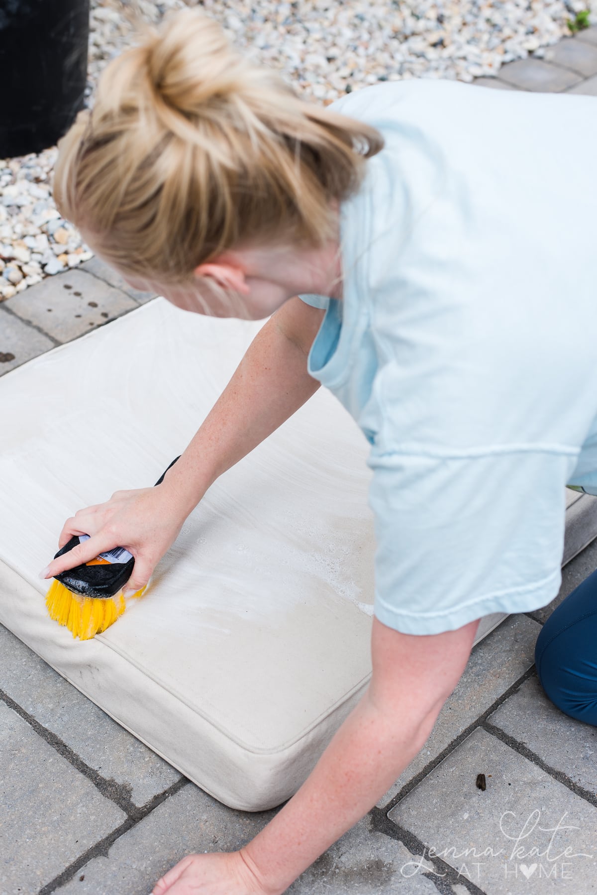 woman cleaning outdoor cushion with soapy water mixture and brush