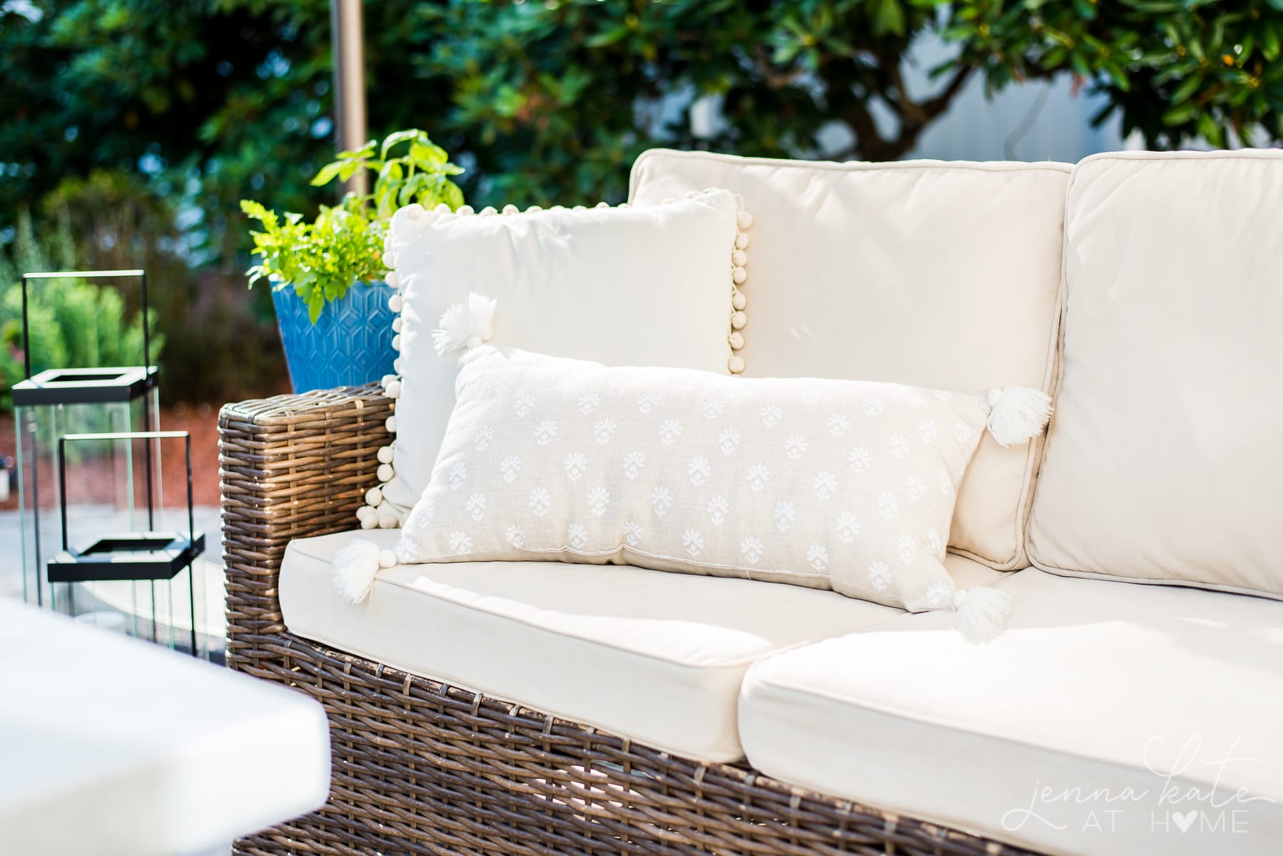 Outdoor cushions on a sectional with accent pillows and a planter of flowers
