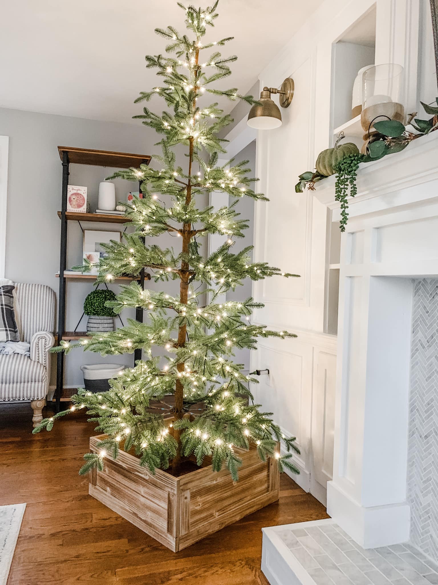 Lit up sparse Christmas tree inside a square wooden tree collar