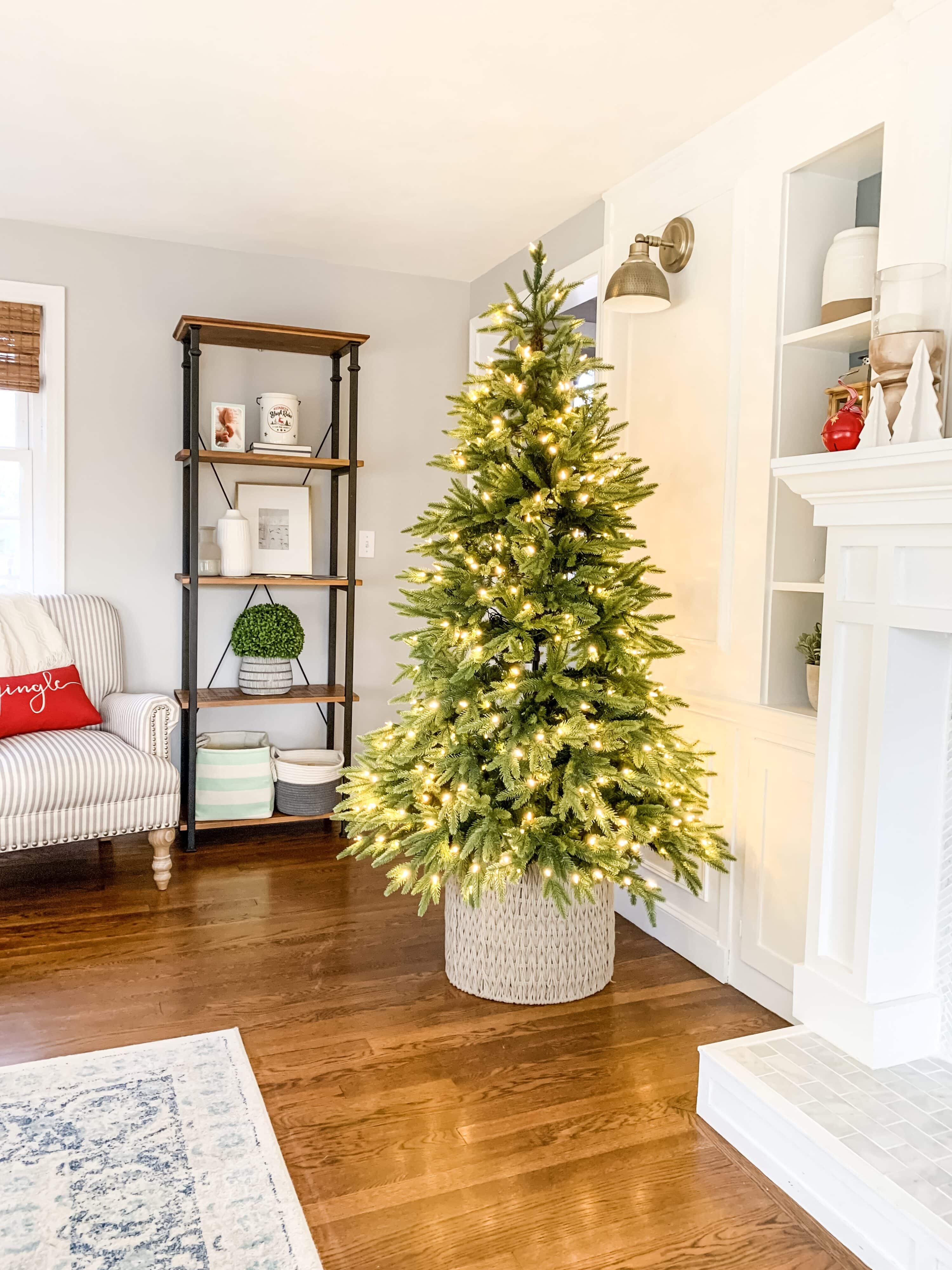 Full looking artificial Christmas tree with lights in a basket. All fluffed and ready for decorations