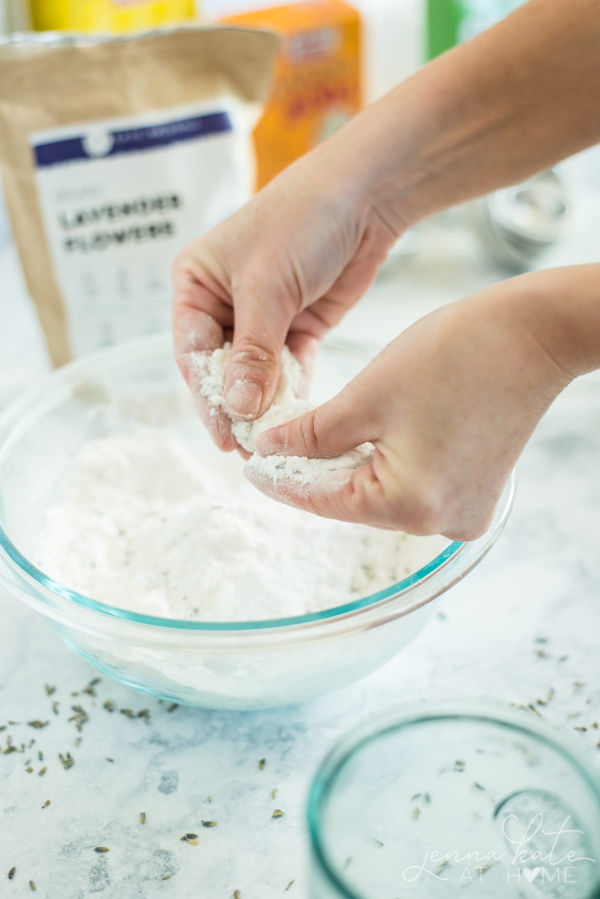 Checking the loose bath bomb mixture in the glass bowl  with your hands to make sure it resembles wet sand