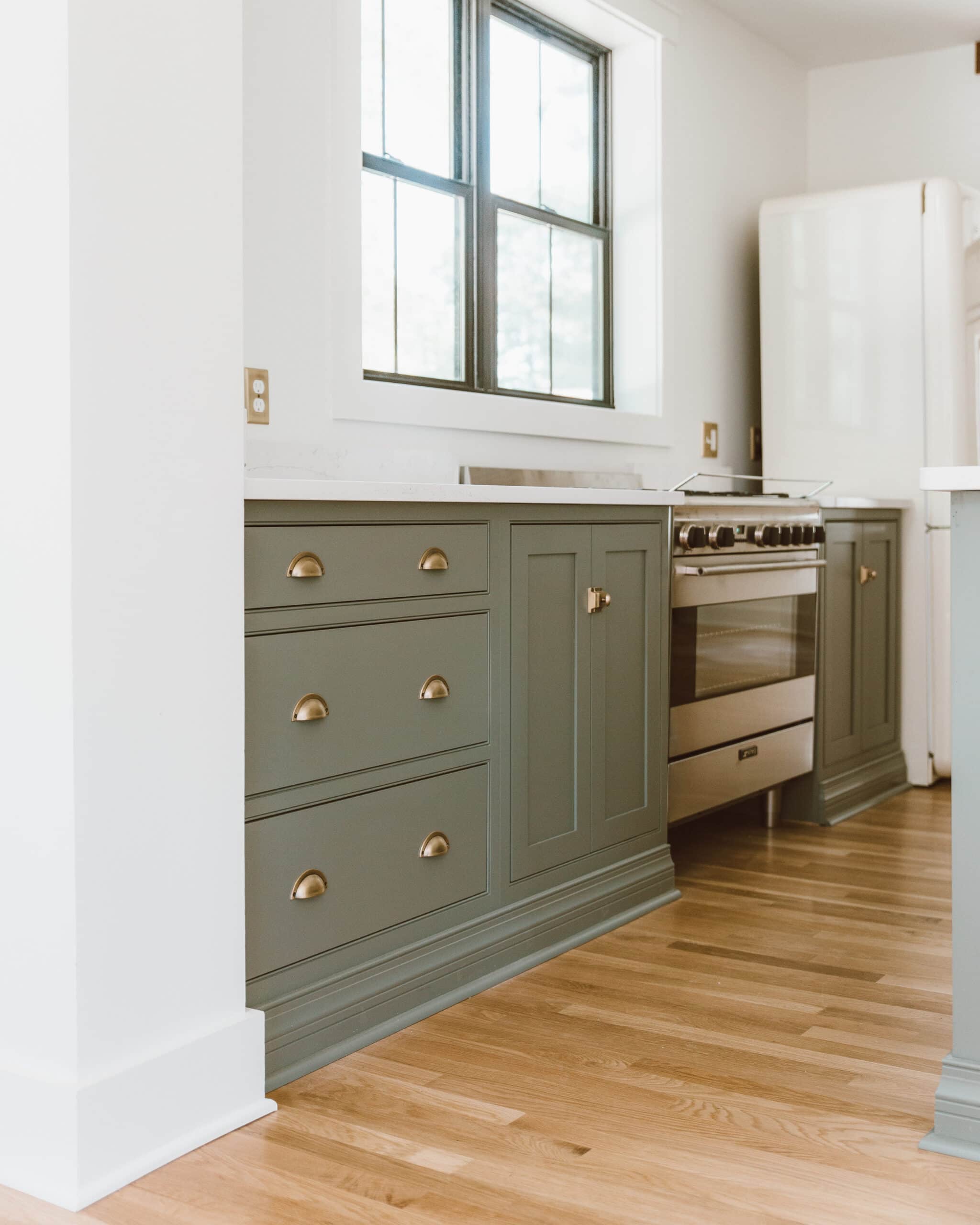 A kitchen with a wood floor and green cabinets