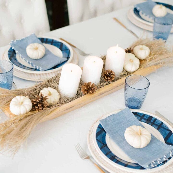 A table setting with a beautiful neutral centerpiece and blue plaid plates.
