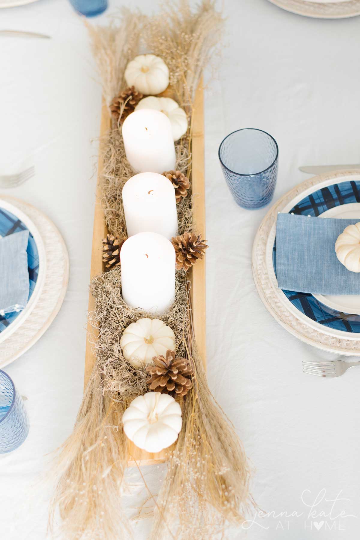 White candles and other neutral colored nature inspired objects in the centerpiece