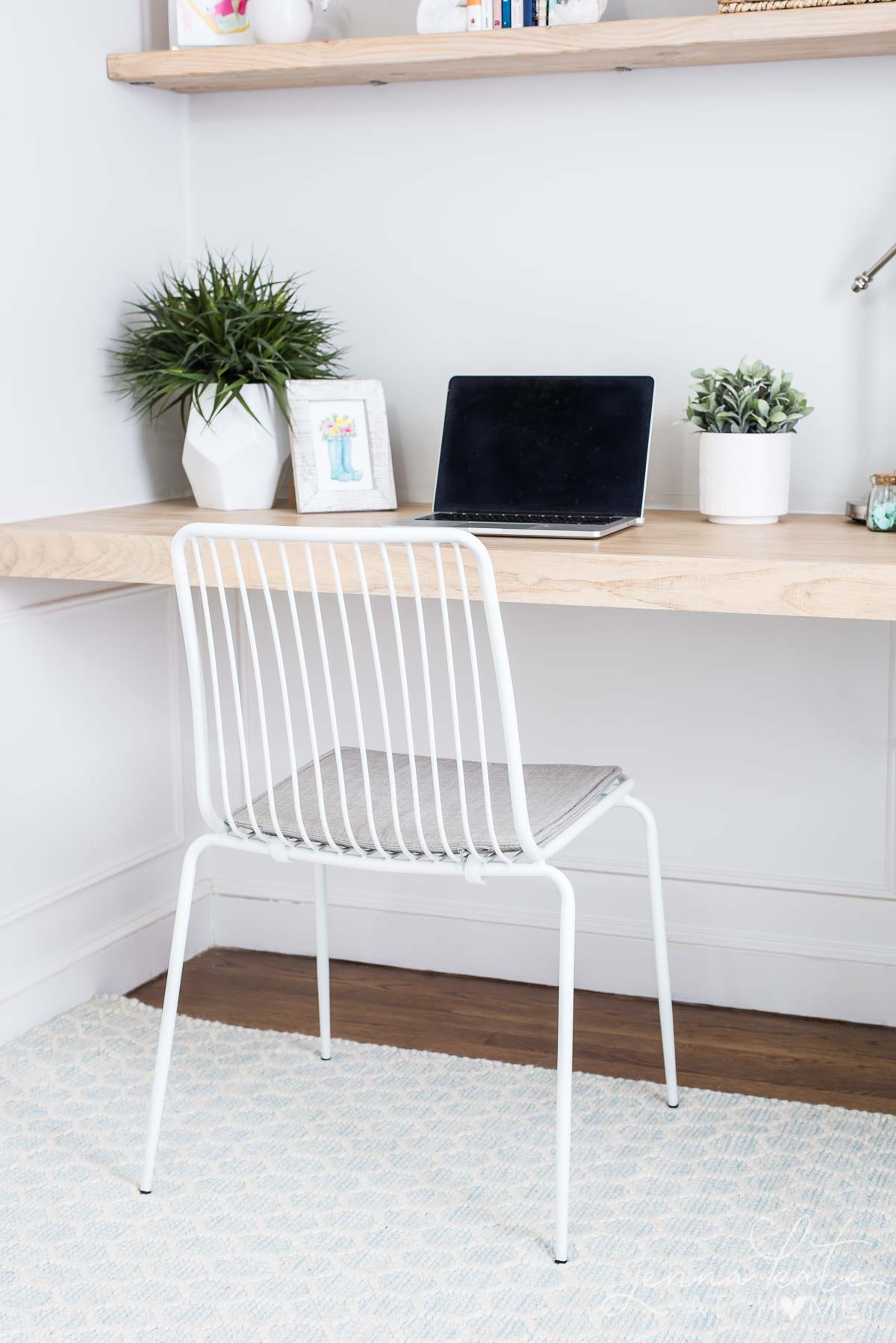 Home office desk nook with floating desk and a white metal chair.