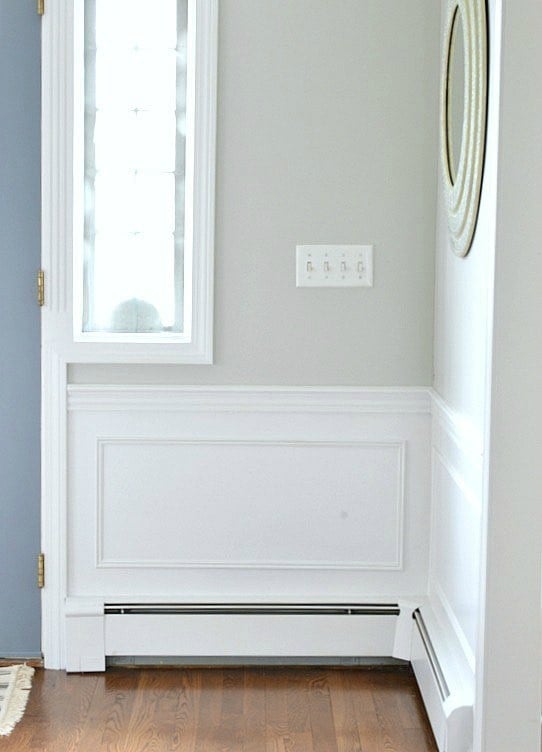 The tall, narrow window near the blue front door of a home with Benjamin Moore Decorator's White Wainscoting and Trim