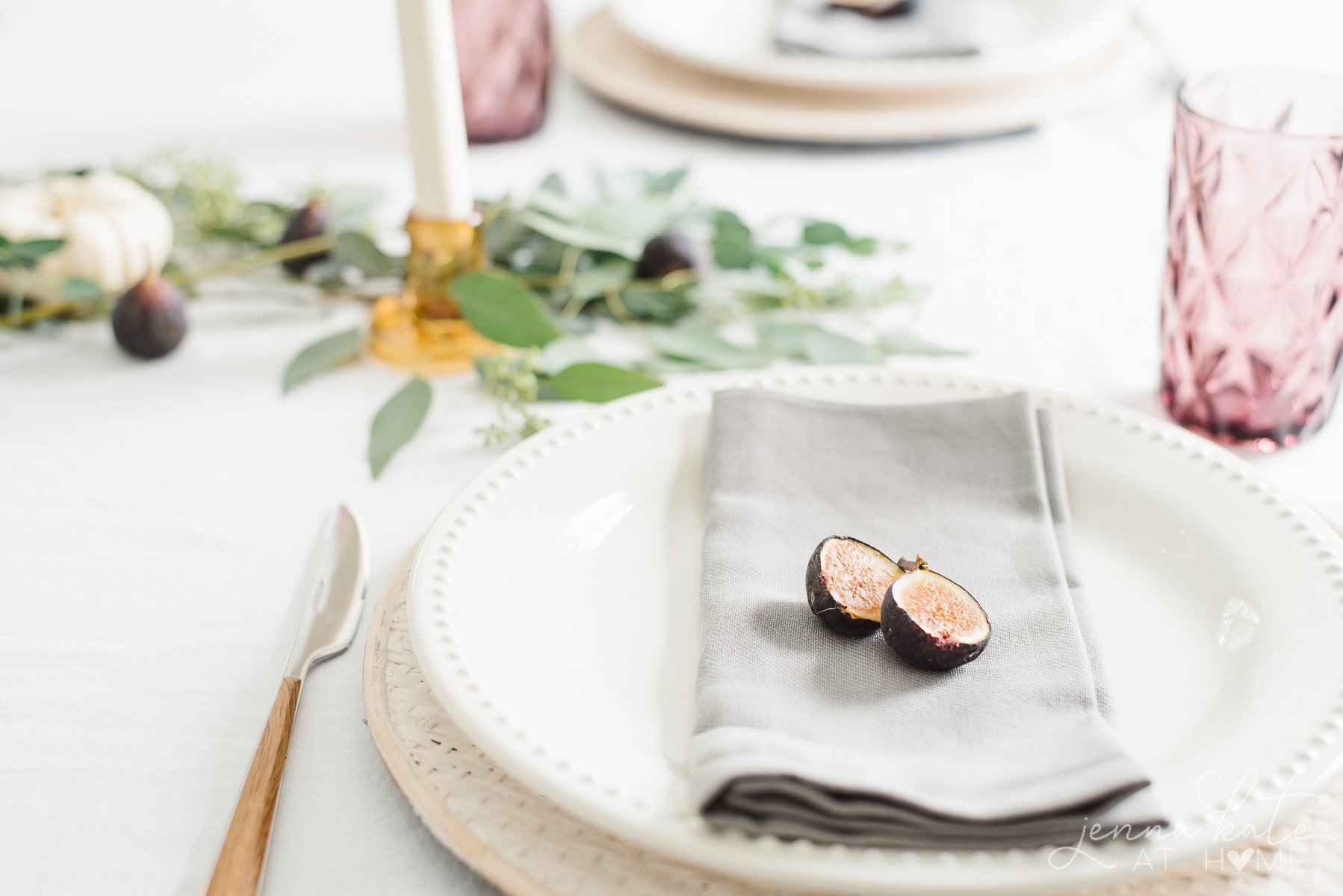 Cut fig on a gray napkin with plum colored glassware