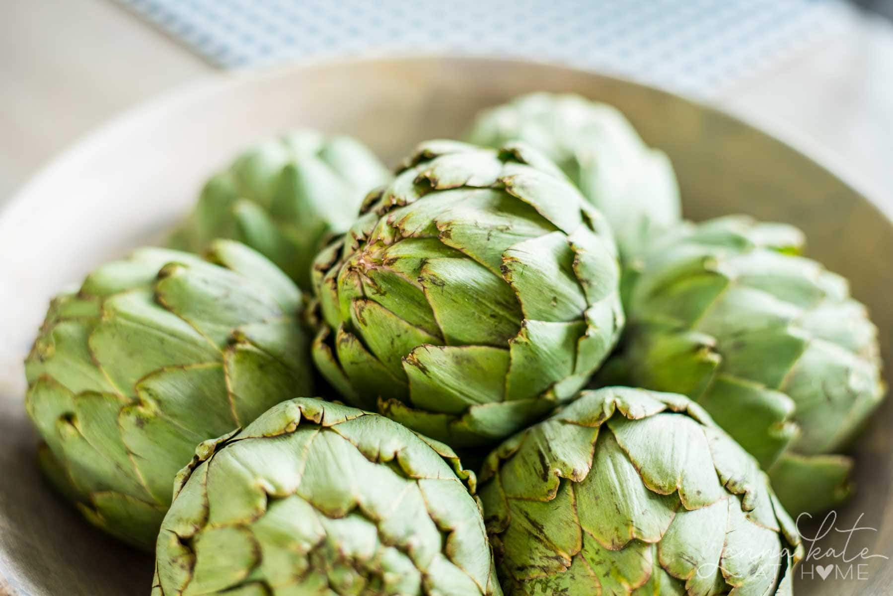 A wooden bowl filled with artichokes